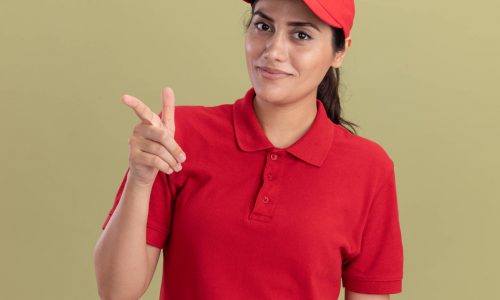 smiling-young-delivery-girl-wearing-uniform-with-cap-points-at-camera-isolated-on-olive-green-wall (1)